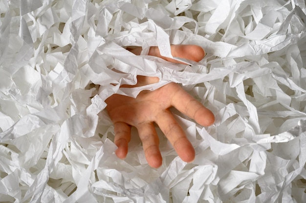 Hand reaches out from heap of shredded paper