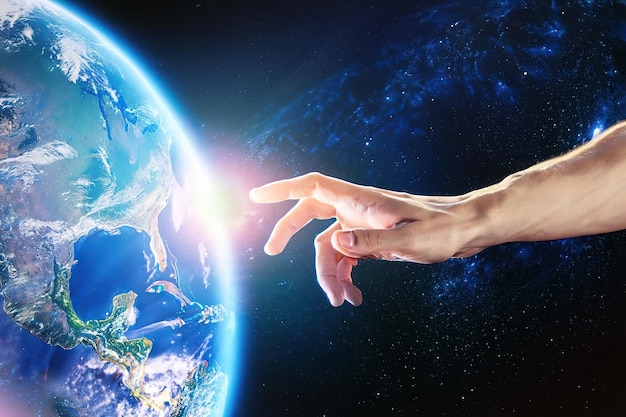 A hand reaches out to touch the earth.