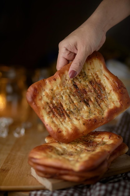 한 손이 피망이 올려진 빵 한 조각을 향해 뻗는다.