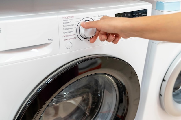 a hand reaches to select a wash cycle on the washing machine