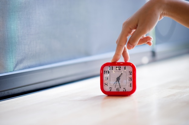 Hand and red alarm clock that shows the alarm at all Every morning, the concept of punctuality