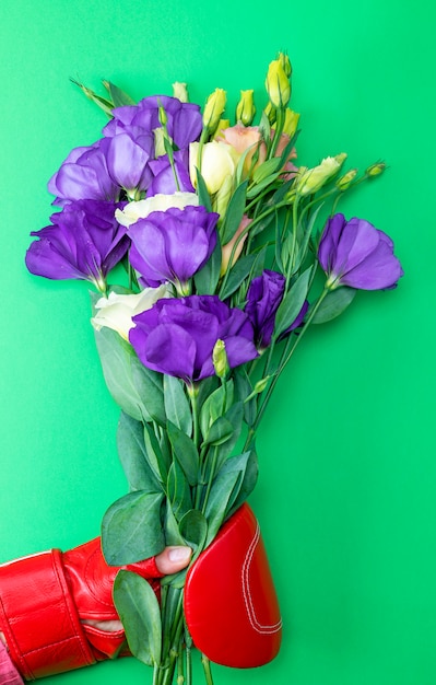 Hand in a red boxing glove holding a bouquet of flowers