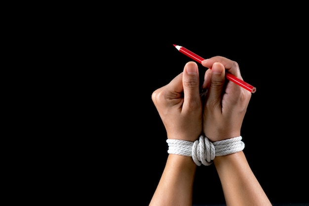 Hand and red pencil tied with rope