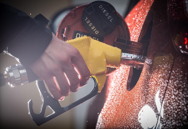 Photo hand refilling the car with fuel closeup