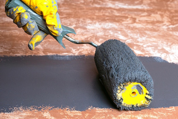 Hand repairman applying paint with a roller closeup