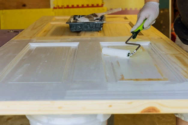 Hand of repairman with gloves of painting doors using hand roller painting in a new house