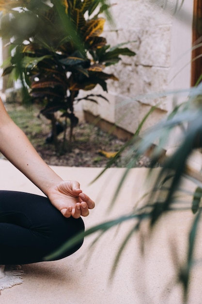 Foto la mano poggiata su un ginocchio in posizione di loto meditando tra fogliame lussureggiante