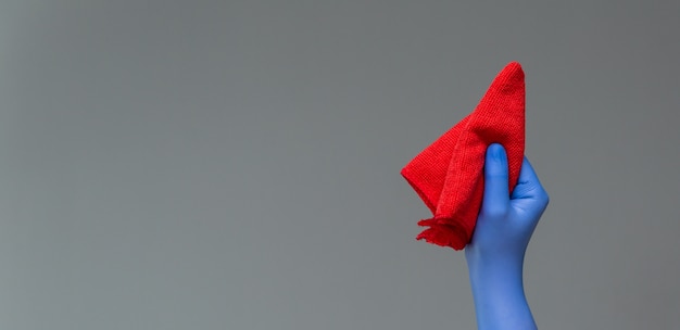 A hand in a rubber glove holds a bright microfiber duster