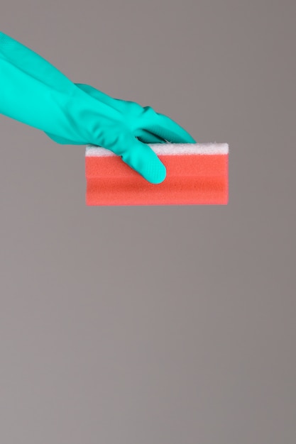 Hand in rubber glove holds color wash sponge on neutral surface. The concept of bright spring.