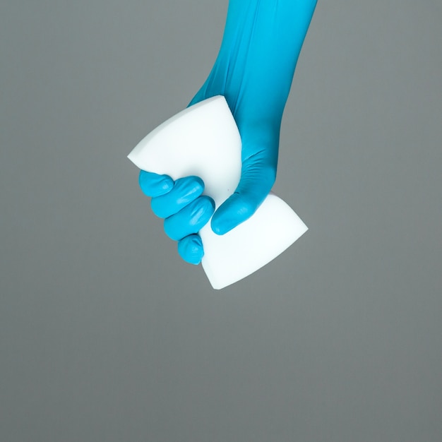 Foto la mano nel guanto di gomma contiene una spugna per il lavaggio dei colori