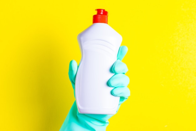 Hand in rubber glove holds dishwashing liquid