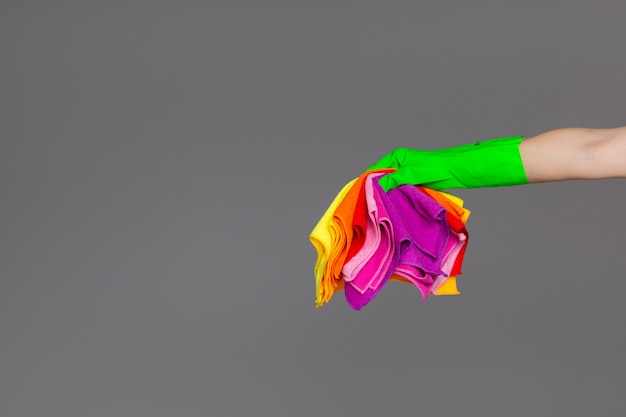 Photo a hand in a rubber glove holds a set of coloured microfibre cloths on neutral.