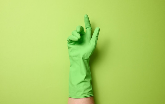 녹색 배경을 청소하기 위해 고무 녹색 장갑을 끼고 몸의 일부가 들어 올려집니다