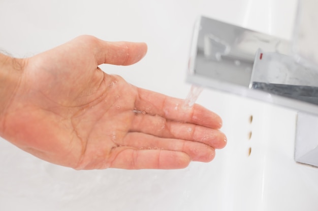 Photo hand under running water at bathroom sink