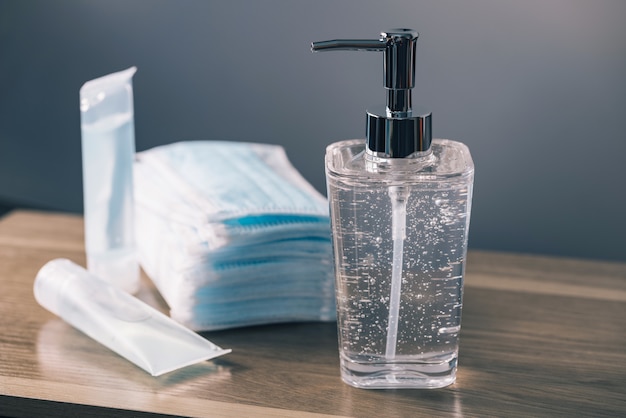 Hand sanitizer and medical surgical masks on a wooden table