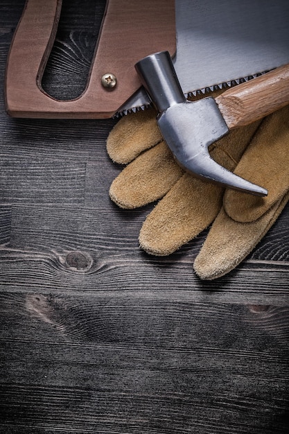 Foto sega a mano martello da carpentiere guanti protettivi in pelle su tavola di legno