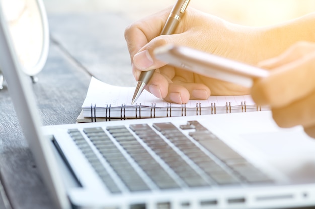 hand schrijven op notitie boek met laptop en smartphone