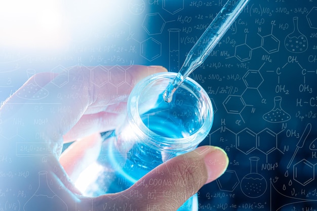 hand of scientist holding flask with lab glassware and test tubes in chemical laboratory background