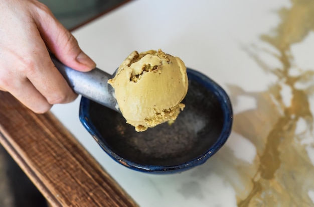 hand scooping a scoop of ice cream into a spoon in fridge