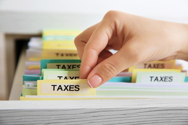 Hand searching through variety of tax documents in open drawer