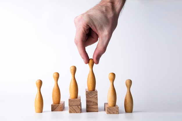 Hand selecting a wooden figure business leadership concept