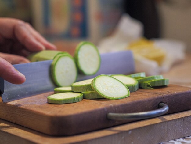 Photo hand of senior woman cutting zucchini