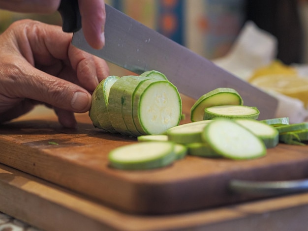 Photo hand of senior woman cutting zucchini