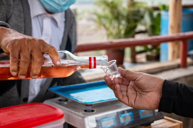 Hand serving a shot of infused alcohol in a market