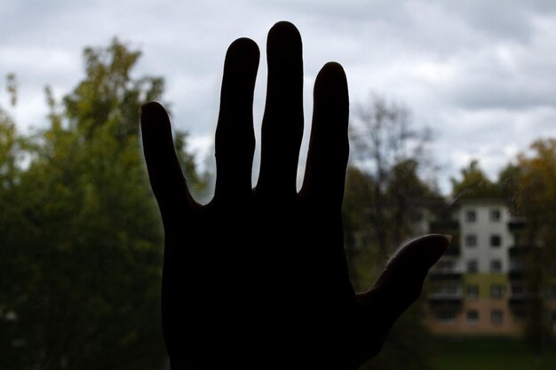 Hand shadow on glass against sky background