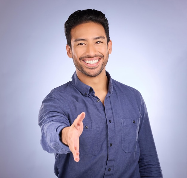 Hand shake welcome and portrait of a business man with happiness from deal agreement Isolated blue background and studio with a young man ready for shaking hands for onboarding or yes hand sign