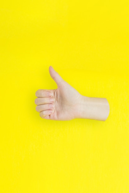 Hand show like or good sign success and nice on yellow background.