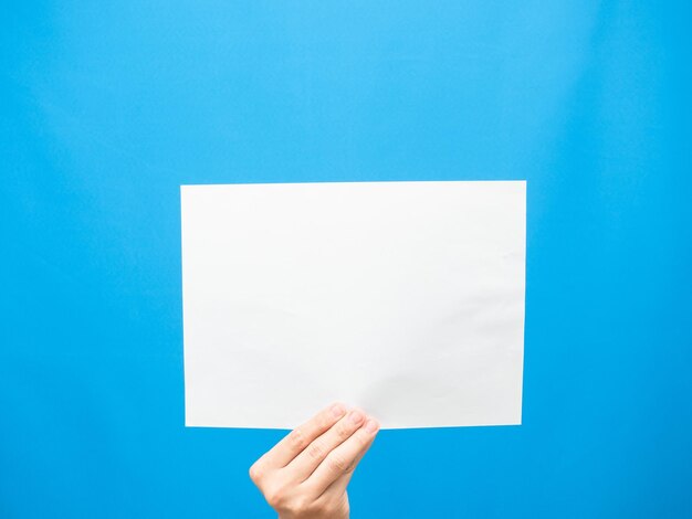 Hand show white paper empty blue background