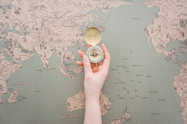 Photo hand showing a compass with world map background