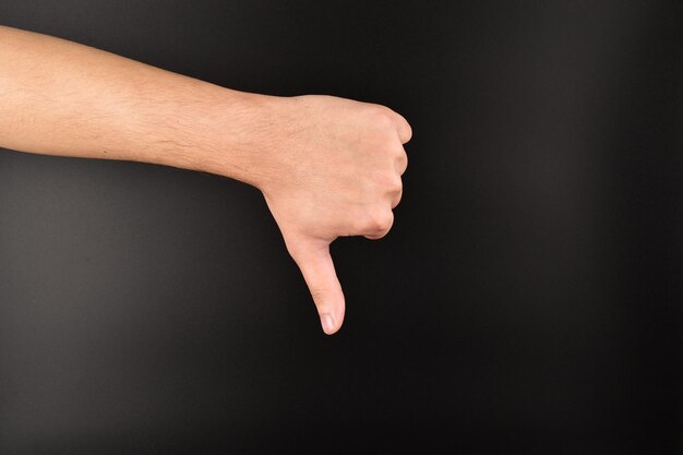 hand showing thumbs down gesture on dark background