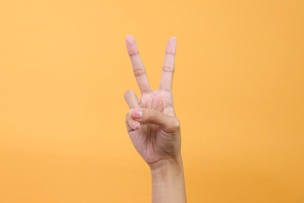 Photo hand showing two fingers isolated on pink background victory and peace gesture