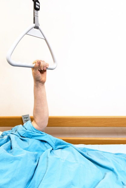 Hand of sick person holds handle of hospital bed