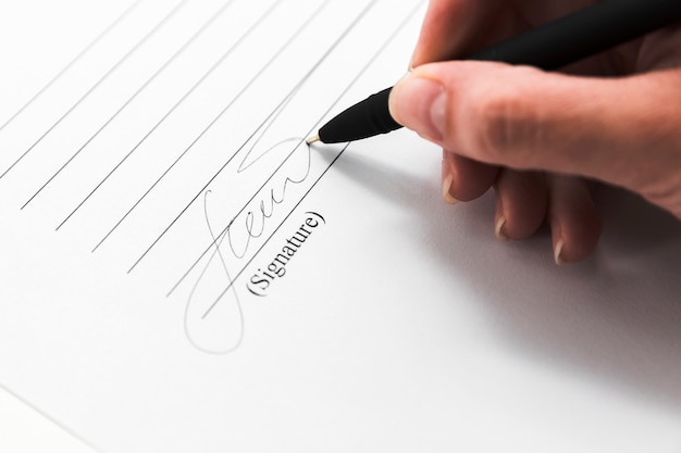 Hand signing a document with a pen