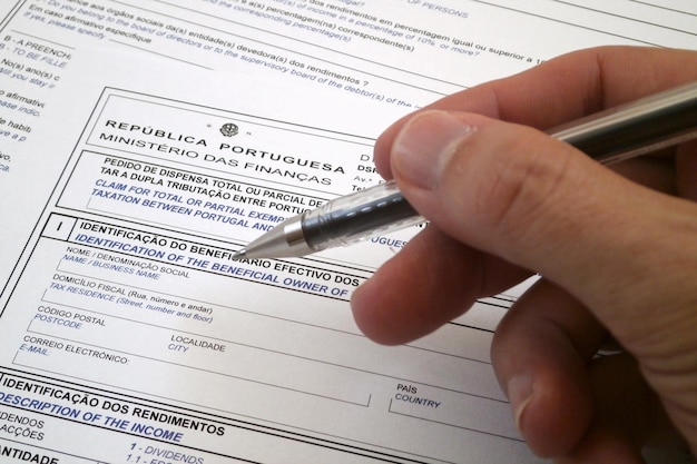 Foto la mano di qualcuno che compila un modulo fiscale portoghese