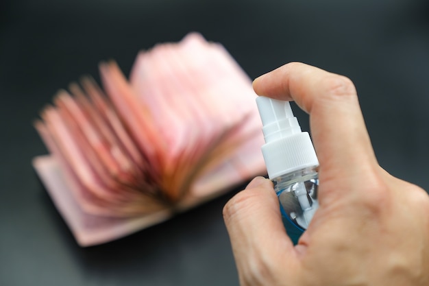 Hand spraying alcohol gel onto banknotes