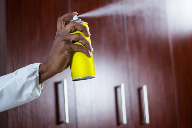 Hand spraying pesticide from a spray can