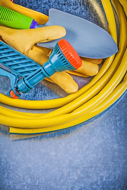 Hand spuiten tuinslang veiligheidshandschoenen spade op metalen achtergrond tuinieren concept