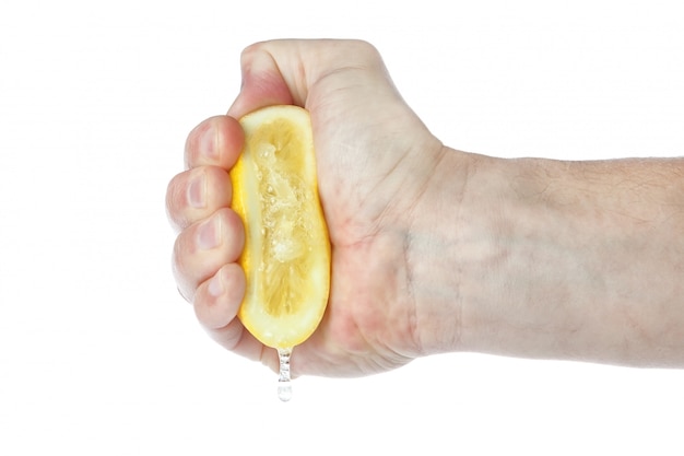 The hand squeezes a lemon. On a white wall.