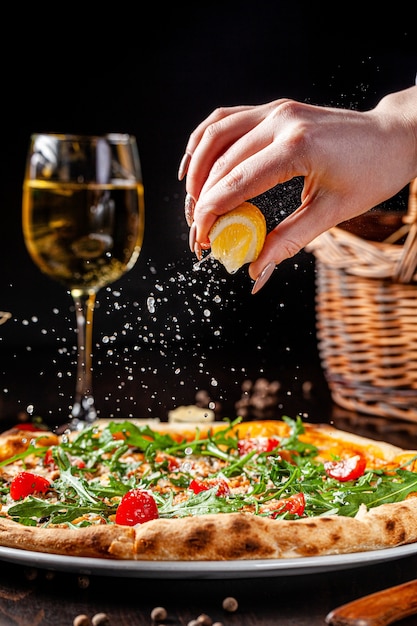 Hand squeezing lemon on a pizza