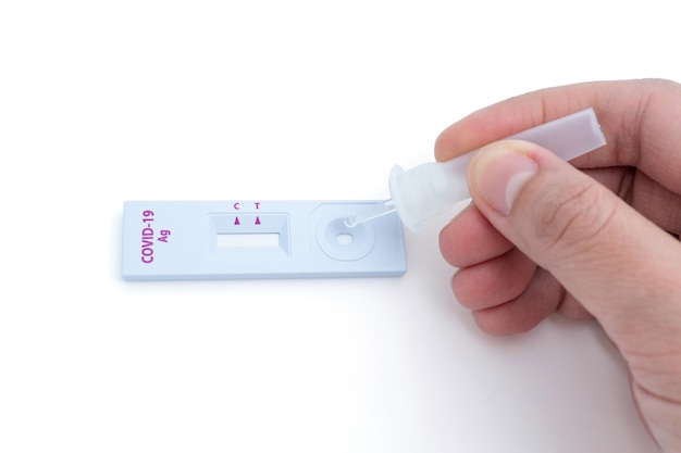 Hand squeezing a tube containing a sample of secretions onto a coronavirus (COVID-19) testing device. It's a quick and easy medical examination. Suitable for use for early or urgent disease screening.