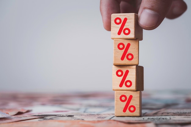 Photo hand stacking red percentage sign symbol on wooden cube block for financial increase interest rating and dividend from investment growth concept