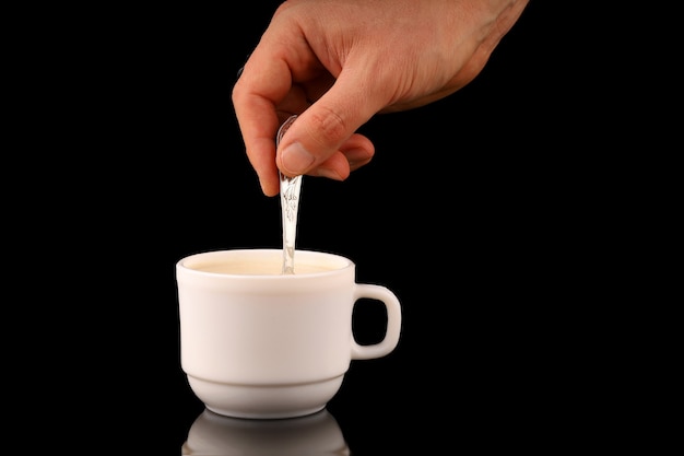 Hand stirs cappuccino in a cup