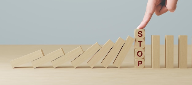 Hand stopt houten domino zakelijk crisiseffect of risicobeveiligingsconcept