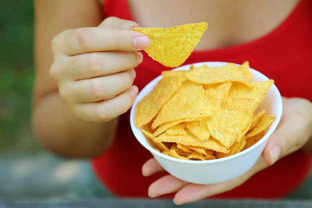 Hand take tortilla chip from a full bowl.