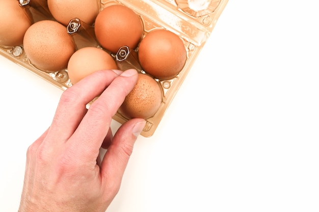 Hand takes chicken egg from egg tray. 