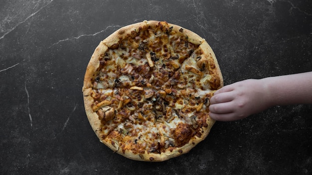 La mano prende un pezzo di pizza su uno sfondo scuro